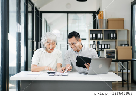 Two business workers talking on tablet and using laptop Two business workers talking on tablet and using laptop 128645963