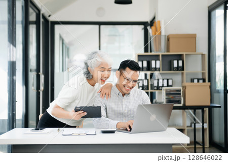 Two business workers talking on tablet and using laptop 128646022