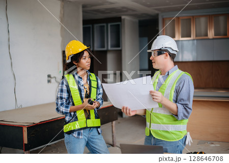 Engineers are discussing data working and laptop or tablet with architectural project at new construction site on big project. Engineers are discussing data working and laptop or tablet with architectural project at new construction site on big project. 128646708