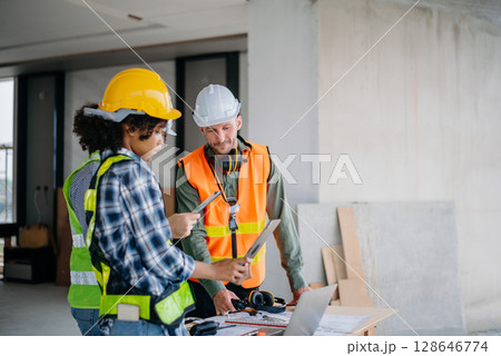 Architect caucasian man working with colleagues mixed race in the construction site. Architecture engineering on big project. Building in construction interior. 128646774