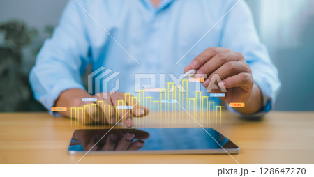 Growth in business performance visualized through a holographic bar graph from a tablet, showing a person analyzing digital data, symbolizing finance, innovation, and strategy. 128647270