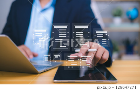 Document management visualized by a person interacting with holographic icons from a tablet, with laptop in background, symbolizing digital workflow, remote work, and paperless efficiency. Document management visualized by a person interacting with holographic icons from a tablet, with laptop in background, symbolizing digital workflow, remote work, and paperless efficiency. 128647271