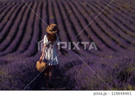 Lavender field woman Provence day, girl walks rows, holding flowers in tote bag, sunny. 128648461
