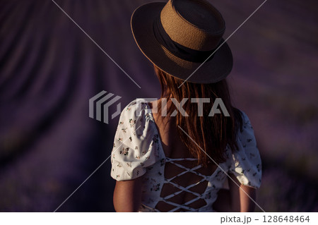 Lavender fields woman: Girl wears hat in summer lavender field, enjoying nature and scenic views. 128648464