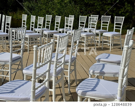 White chairs for the guests of the wedding ceremony are on the site. High quality photo White chairs for the guests of the wedding ceremony are on the site. High quality photo 128648839