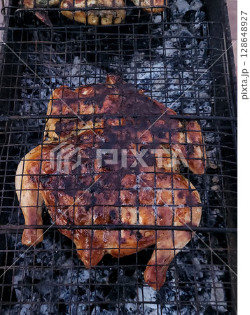 Tobacco chicken is grilled on a charcoal grill in the backyard Tobacco chicken is grilled on a charcoal grill in the backyard 128648927