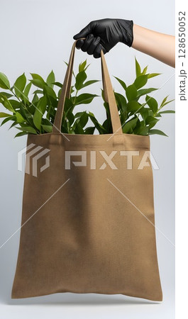 hand holding paper bag with green plant leaves 128650052