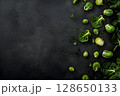 Fresh green Brussels sprouts and leafy vegetables scattered on a dark textured surface, showcasing vibrant colors and natural textures for culinary inspiration and healthy eating 128650133