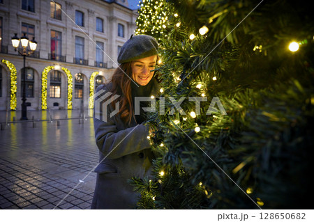 Woman enjoying Christmas decorations on festive street 128650682
