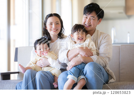 木のぬくもりのある新築のような家の自宅のソファーでくつろぐ4人の日本人家族 カメラ目線の笑顔 木のぬくもりのある新築のような家の自宅のソファーでくつろぐ4人の日本人家族 カメラ目線の笑顔 128653823
