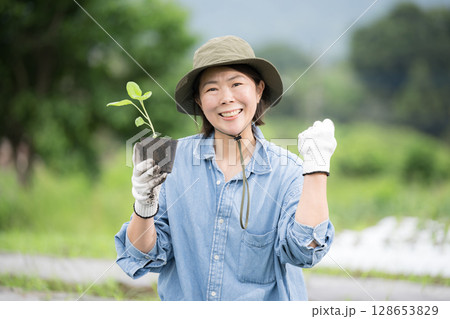 畑でナスの苗植え作業する女性　農家や農業で働くする人のイメージ　カメラ目線	 128653829