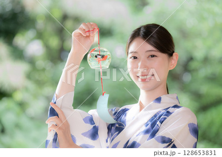 風鈴をを持ってカメラ目線で微笑む浴衣の女性	 128653831