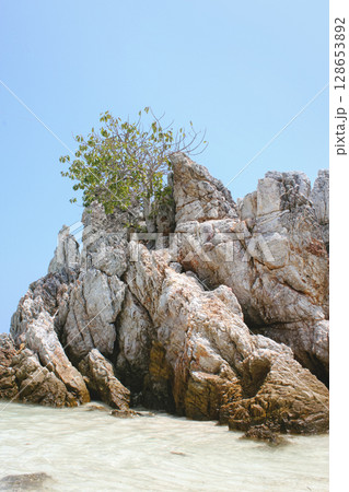 Scenic view of a stunning limestone rock island rising from the turquoise waters of Thailand. Exotic tropical seascape with dramatic cliffs, lush greenery, and crystal-clear ocean 128653892
