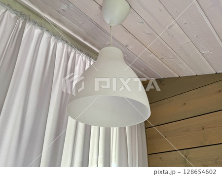 a white plastic ceiling lamp hangs on the ceiling. High quality photo a white plastic ceiling lamp hangs on the ceiling. High quality photo 128654602