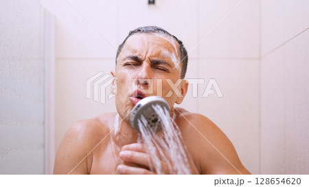 Man singing in shower using showerhead as microphone Man singing in shower using showerhead as microphone 128654620