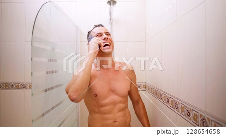 Man laughing while talking on mobile phone in shower Man laughing while talking on mobile phone in shower 128654658