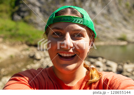 Excited Young Woman Taking Selfie by Mountain River 128655144