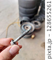 Broken wheel attachment screw. Screw in hand, Car breakdown. 128655261