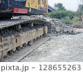 Metal excavator track background. Construction site ground. Heavy machinery equipment. 128655263