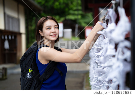 神社でおみくじを結ぶインバウンドの女性 128655688