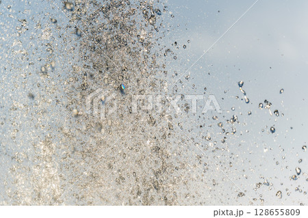 Splashes and jets of water against light background. Splashes and jets of water against light background. 128655809