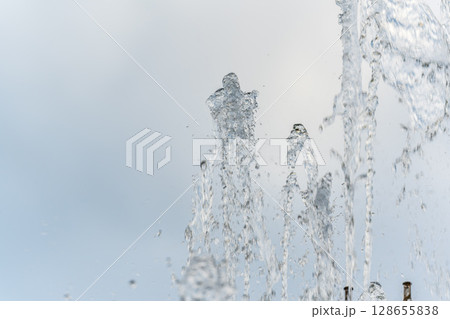 Splashes and jets of water against light background. Splashes and jets of water against light background. 128655838