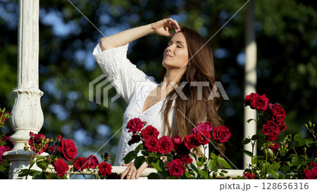 Woman enjoying summer sun among red roses Woman enjoying summer sun among red roses 128656316