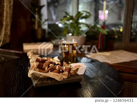 Enjoying delicious fried snacks accompanied by flavorful dips and a refreshing cold beer in an inviting cozy setting 128656431