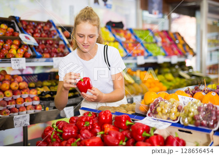 Girl customer buying red pepper at grocery shop Girl customer buying red pepper at grocery shop 128656454