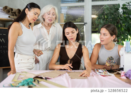 Adult woman teacher explains to group how to make pattern Adult woman teacher explains to group how to make pattern 128656522