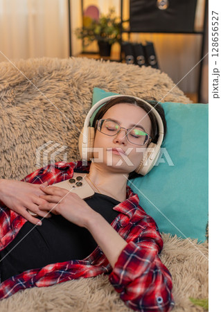 Woman listening to audiobook with wireless headphones at home, nodding with interest full attention 128656527