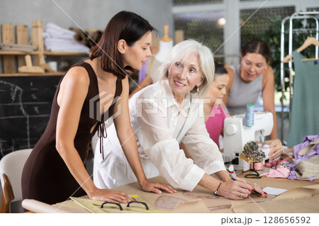 Elderly female teacher explains to group how to draw pattern 128656592