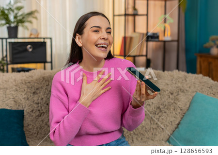 Young woman on sofa talking on speakerphone emotionally sharing story and gesturing with her hands Young woman on sofa talking on speakerphone emotionally sharing story and gesturing with her hands 128656593