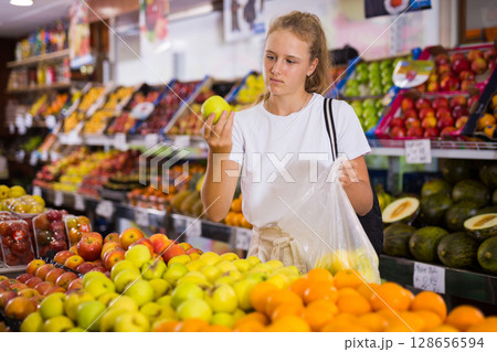 Focused fifteen-year-old girl chooses ripe apples Focused fifteen-year-old girl chooses ripe apples 128656594