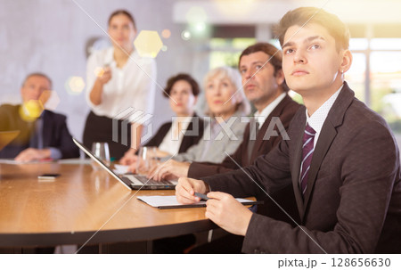 Group of businessmen attentively watching a presentation in meeting room Group of businessmen attentively watching a presentation in meeting room 128656630