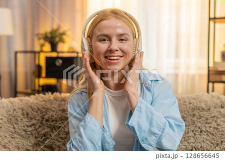 Young woman enjoying calm tunes at home, closed eyes, gentle sway, peaceful vibe, sofa relaxation Young woman enjoying calm tunes at home, closed eyes, gentle sway, peaceful vibe, sofa relaxation 128656645
