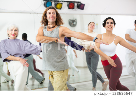 Group of adult people practices dance aerobics 128656647