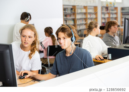 Portrait of a fifteen-year-old schoolboy in headphones at a computer Portrait of a fifteen-year-old schoolboy in headphones at a computer 128656692