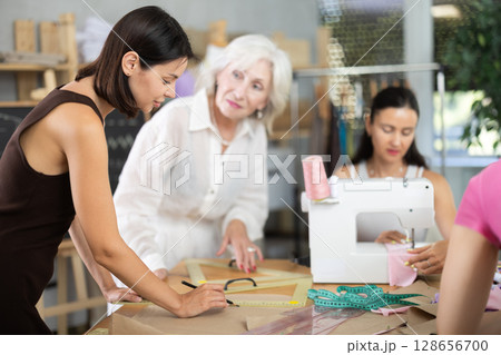 Adult woman teacher explains to group how to draw pattern Adult woman teacher explains to group how to draw pattern 128656700