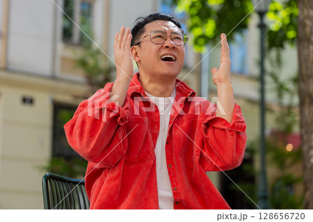 Sad unhappy frustrated Asian man sitting alone in city street, feeling bad, annoyed, grief, problem Sad unhappy frustrated Asian man sitting alone in city street, feeling bad, annoyed, grief, problem 128656720