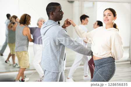 Girl learning to dance waltz paired with african american man Girl learning to dance waltz paired with african american man 128656835