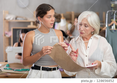 Sewing teacher reviewing pattern with student during class Sewing teacher reviewing pattern with student during class 128656852