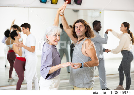 Caucasian man and mature woman rehearsing latin paired dance moves 128656929