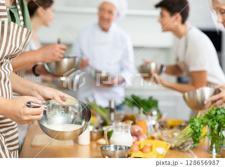 Chef apprentices learn how to properly beat eggs with a whisk in cooking class 128656987