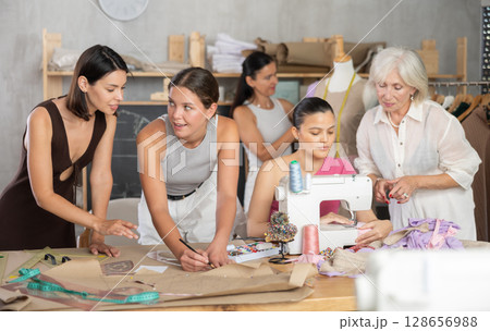 Group of women sew, draw pattern and work with mannequin Group of women sew, draw pattern and work with mannequin 128656988