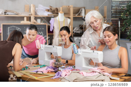 Group of busy women sewing and drawing with teacher at dressmaking courses 128656989