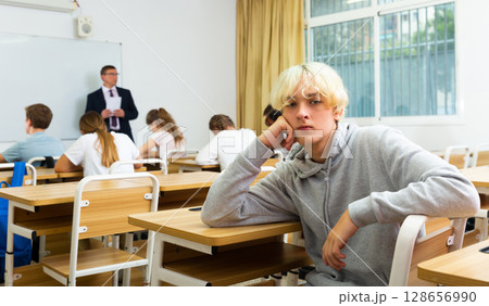 Portrait of disgruntled teenager boy at classroom 128656990