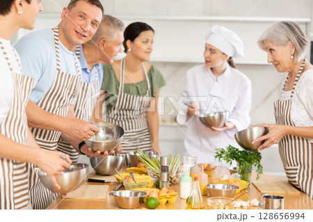 Smiling man learning culinary skills from professional chef at culinary class Smiling man learning culinary skills from professional chef at culinary class 128656994