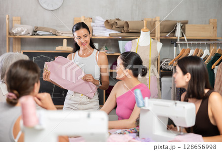 Middle-aged female teacher showing how to make dress detail 128656998