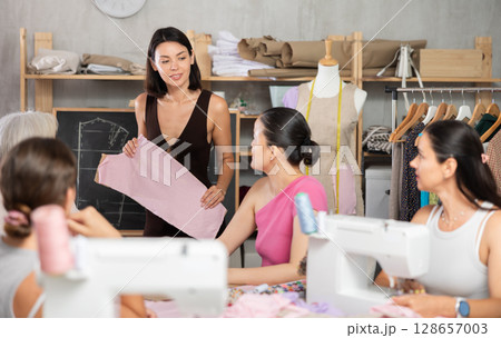 Female instructor explaining garment construction at blackboard during sewing class 128657003